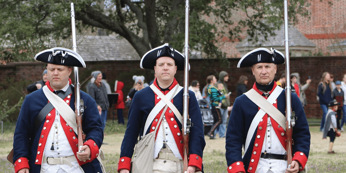 Three American Revolution actors dressed as soldiers holding rifles