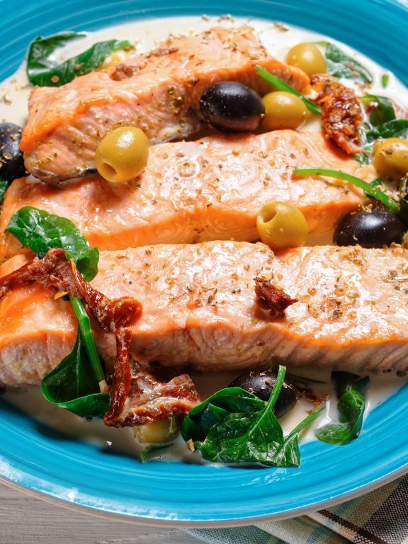 Baked salmon with cream sauce, olives, spinach