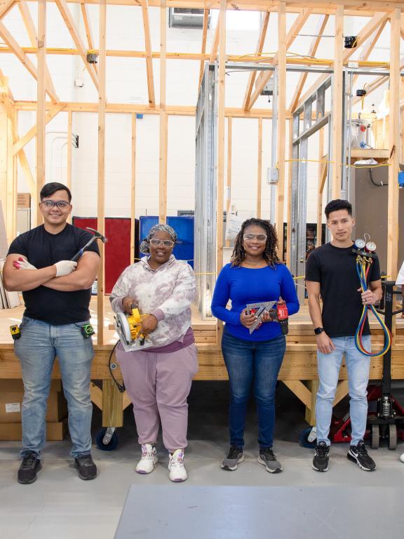 Students in different trades programs stand in front of wooden structure