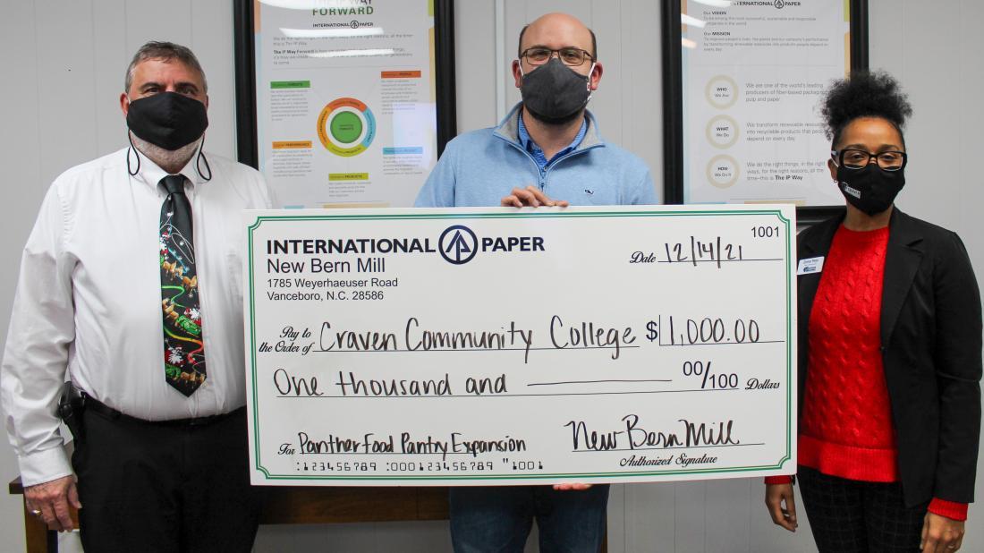 Craven CC Executive Director of Institutional Advancement Charles Wethington (left) and Dean of Student Services Zomar Peter (right) accept International Paper's donation to the college's Panther Pantry from Adam Miklos, mill manager, New Bern mill.