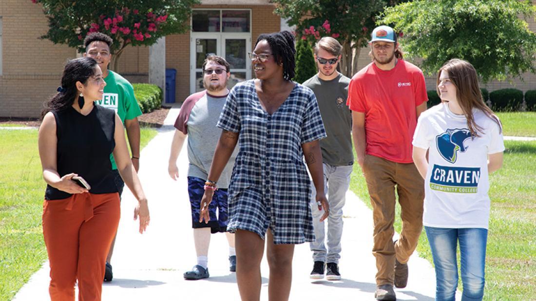 Group of happy students walking down path on campus