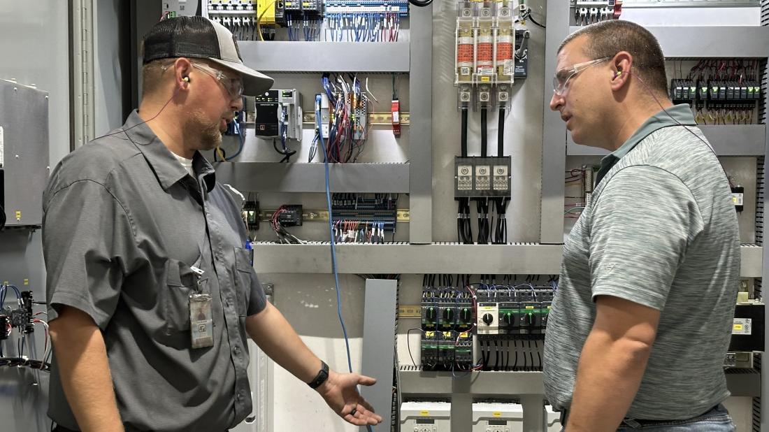 Chatsworth employees Cody Marshall and Stephen Calabro stand in front of an industrial control panel