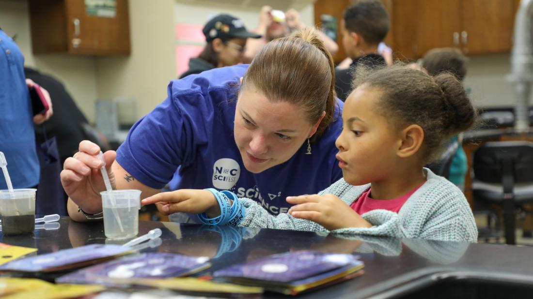 Science instructor Jessica Cofield does a science experiment with a young girl during STEM Night event in April 2025