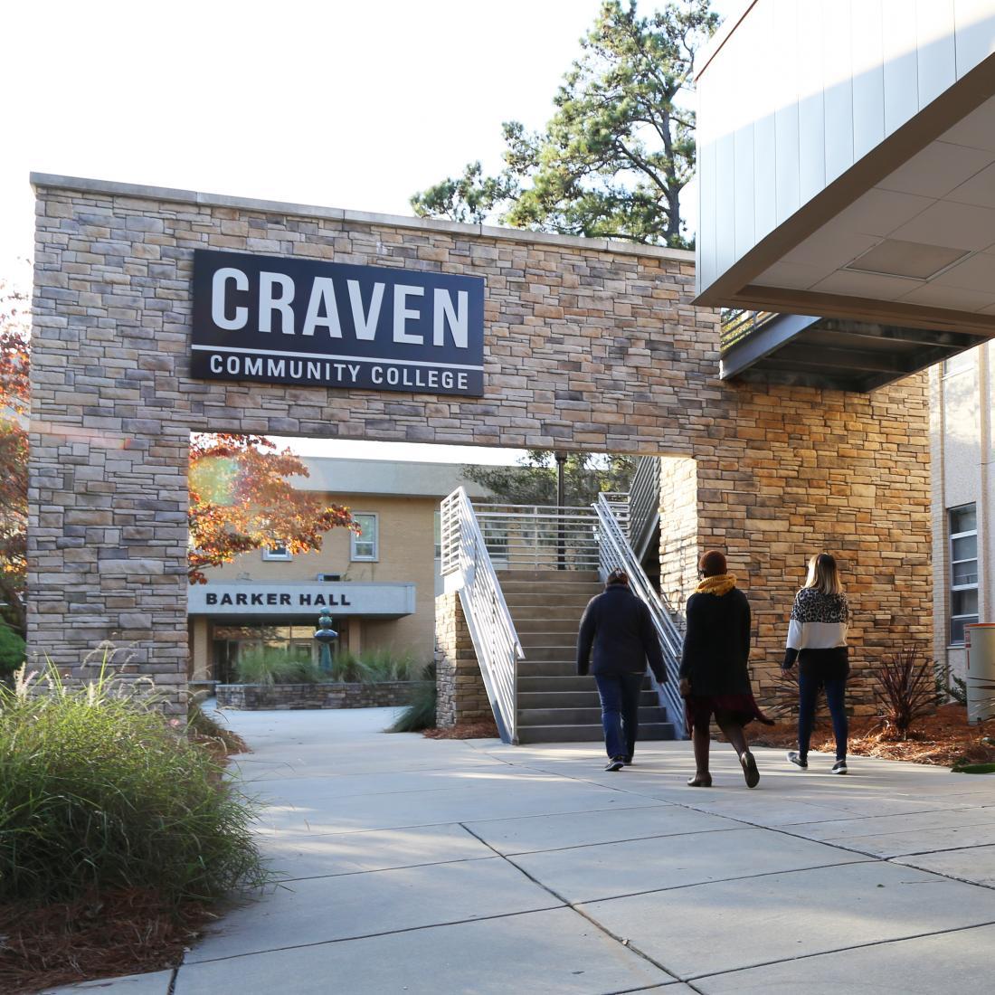 Students walking outside under exterior sign