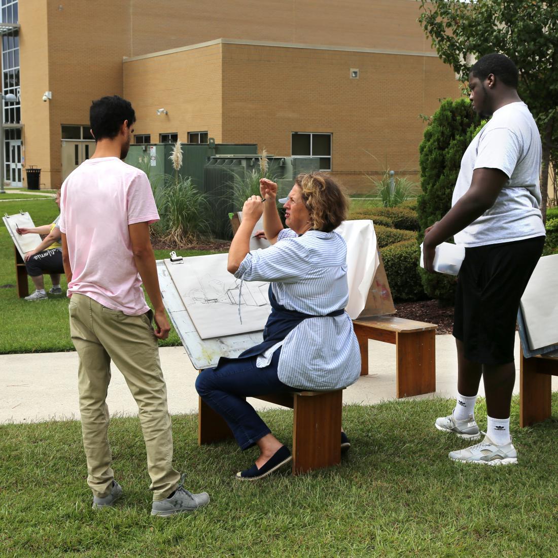 Art instructor at easel with two students