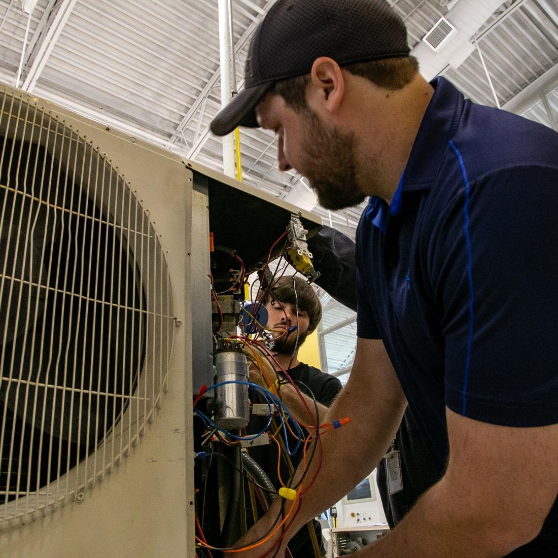 HVAC students work on an air conditioning unit