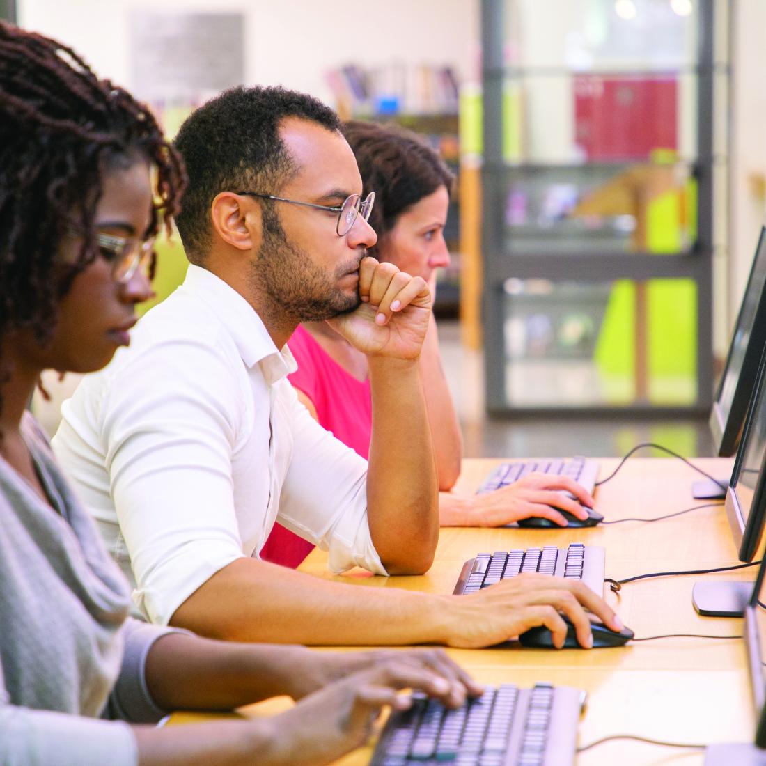 Three young adults work on computers