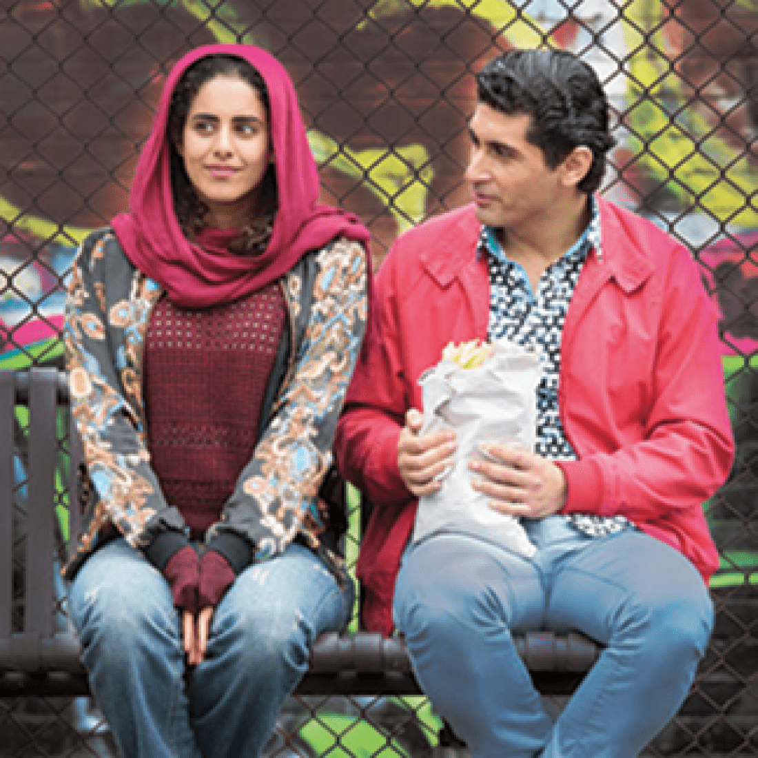 Ali's Wedding promo photo with woman in pink hajib sitting on bench next to man