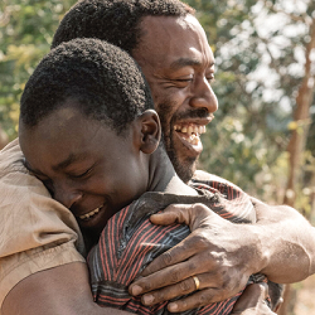 The Boy Who Harnessed the Wind movie promo of smiling man hugging smiling adolescent