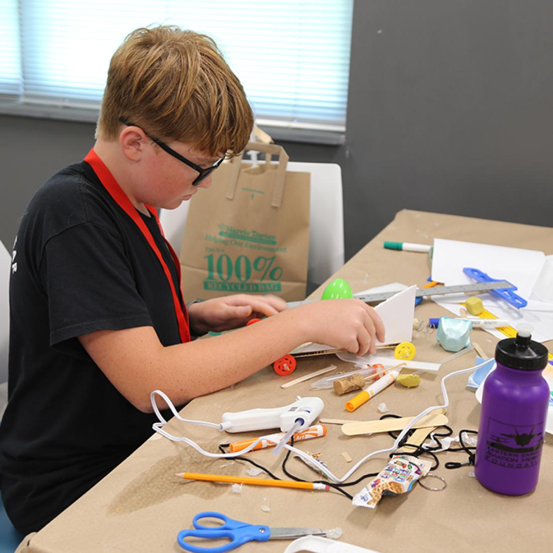 Boy using hot glue gun on craft
