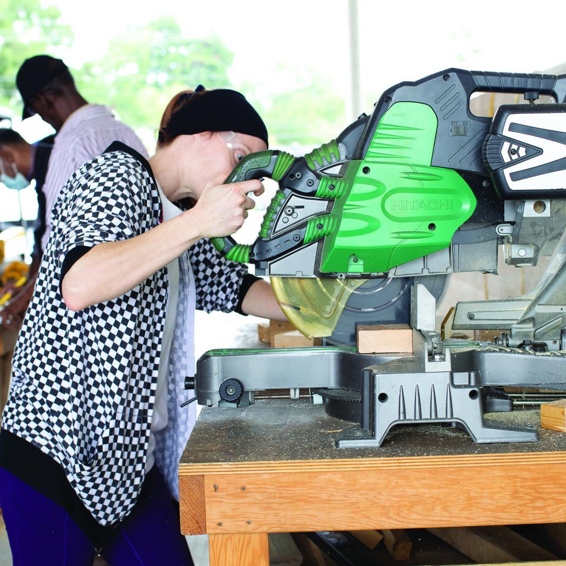 Female carpentry student uses a table saw