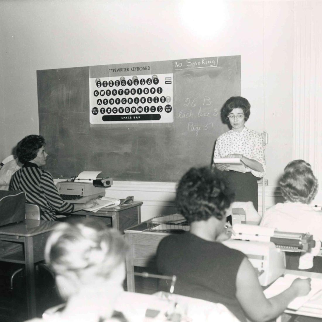 Female instructor speaks to typewriting class in 1970s