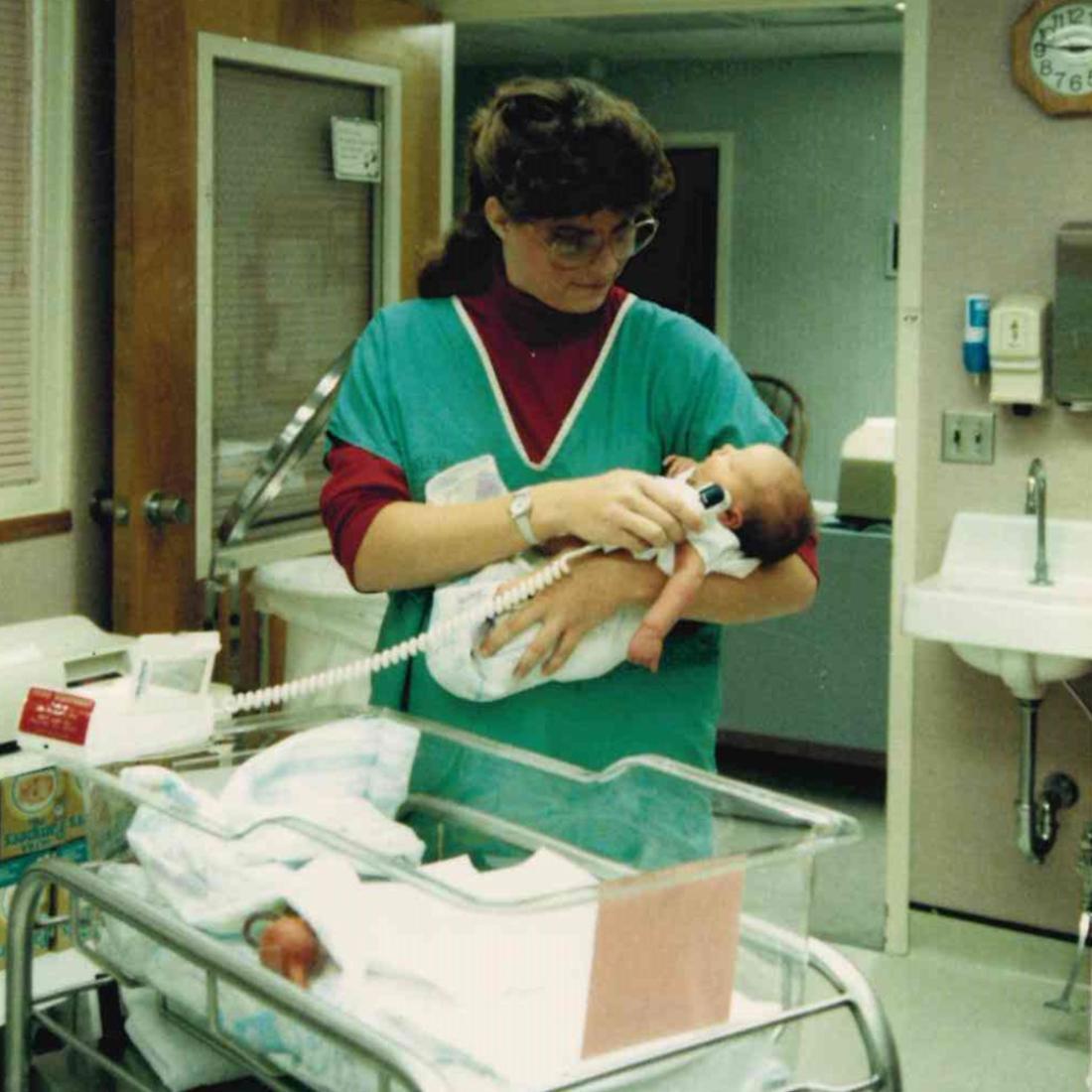 Female nurse taking a newborn's temperature in 1989