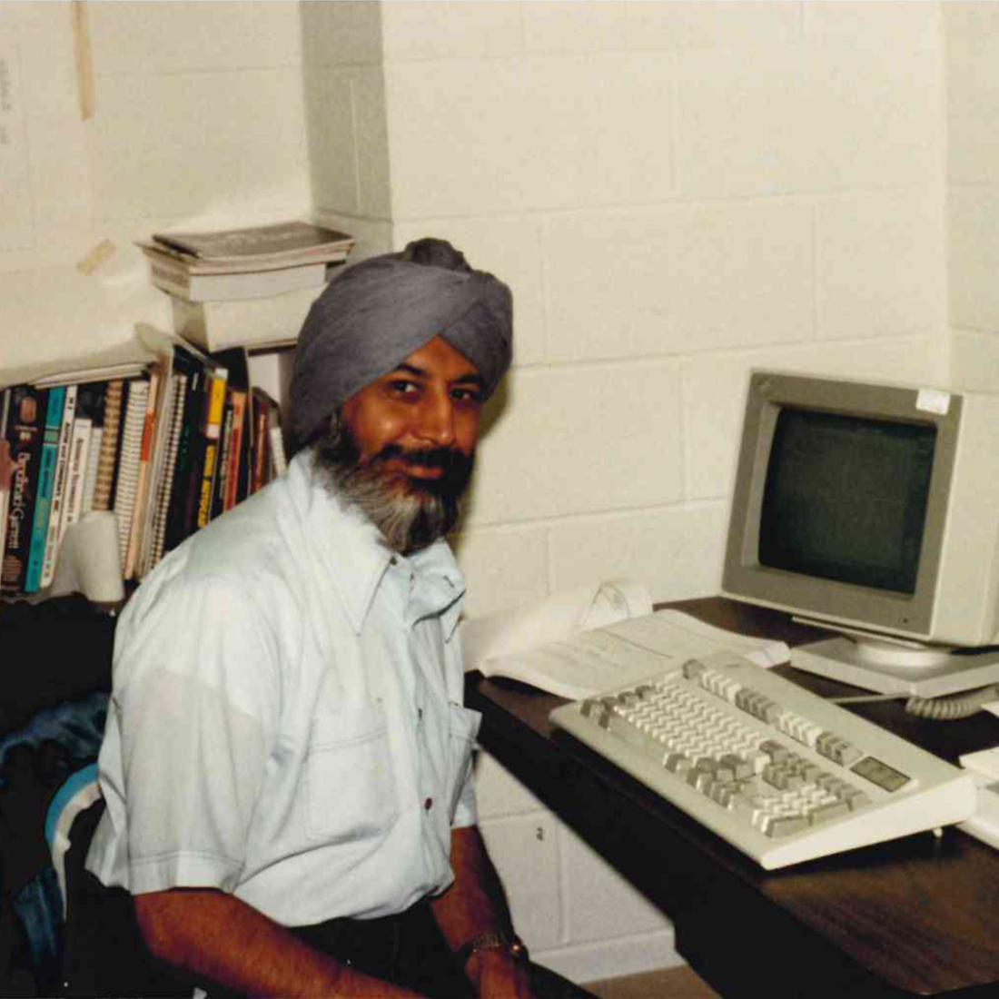 Male teacher in headscarf sitting by computer