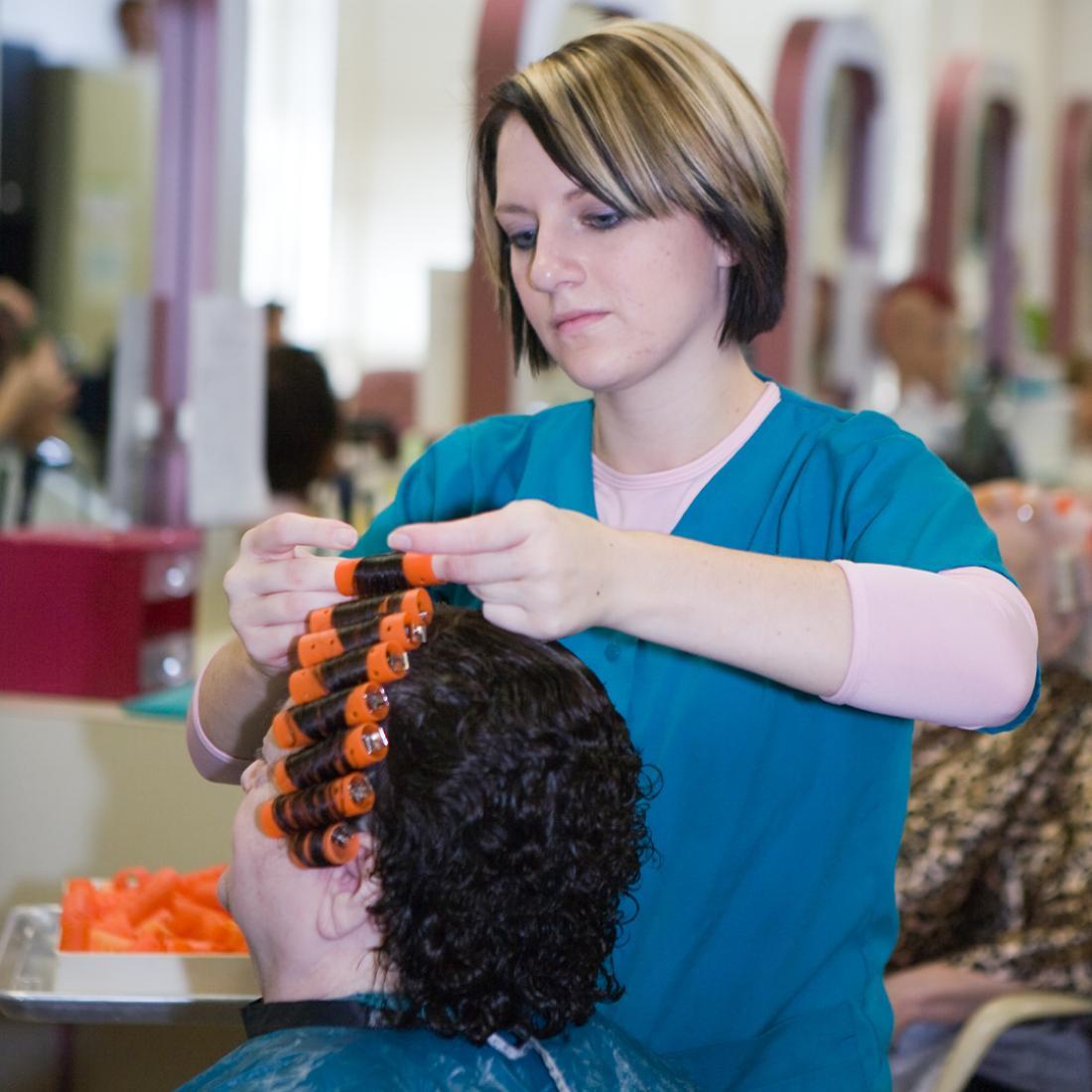 Cosmetology student puts rollers in mannequin's hair in 2010s