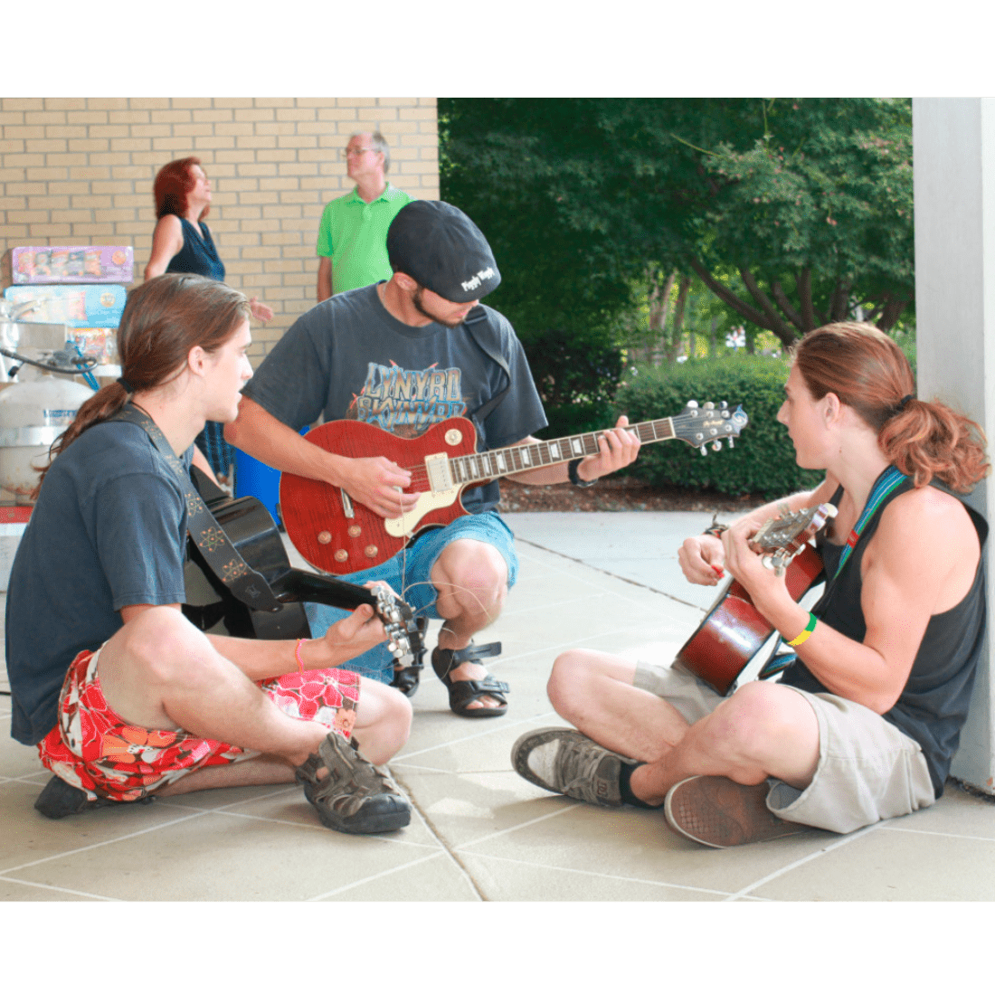 Three male students playing guitars in the courtyard in 2010s