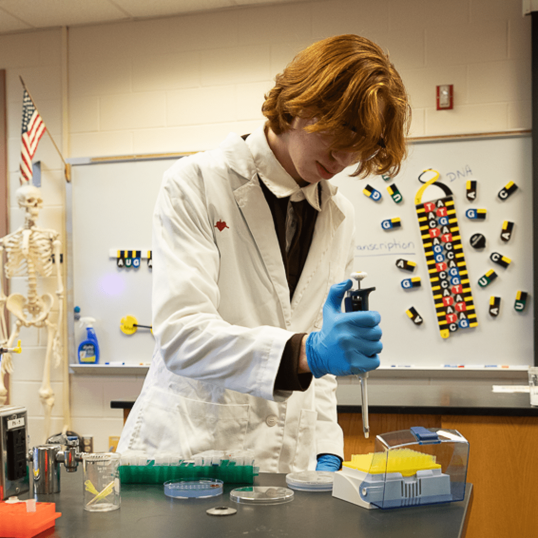 Student wearing white lab coat does a biology experiment
