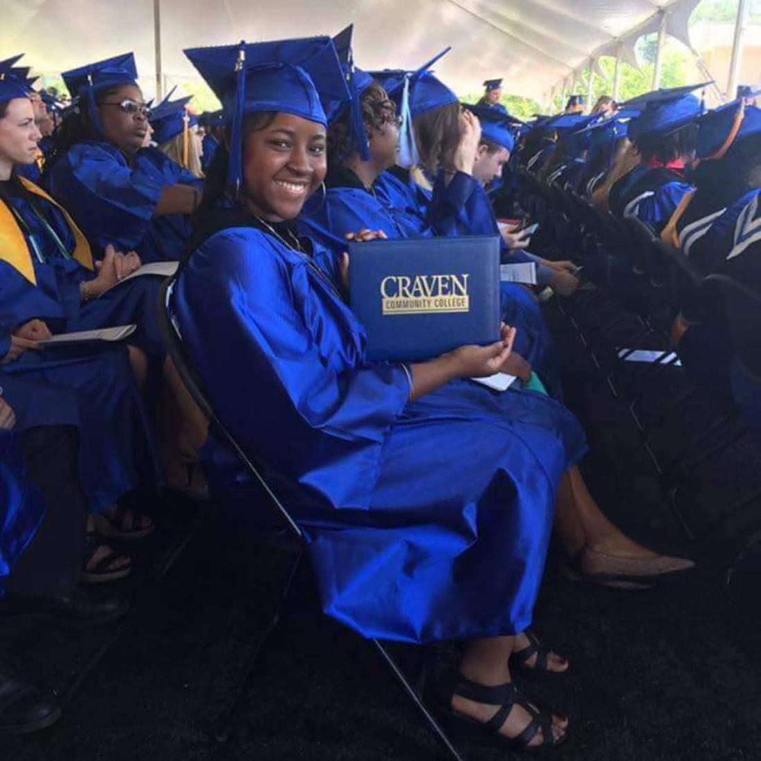 Craven CC employee Rodnekia Stewart shows off her diploma holder during her commencement ceremony