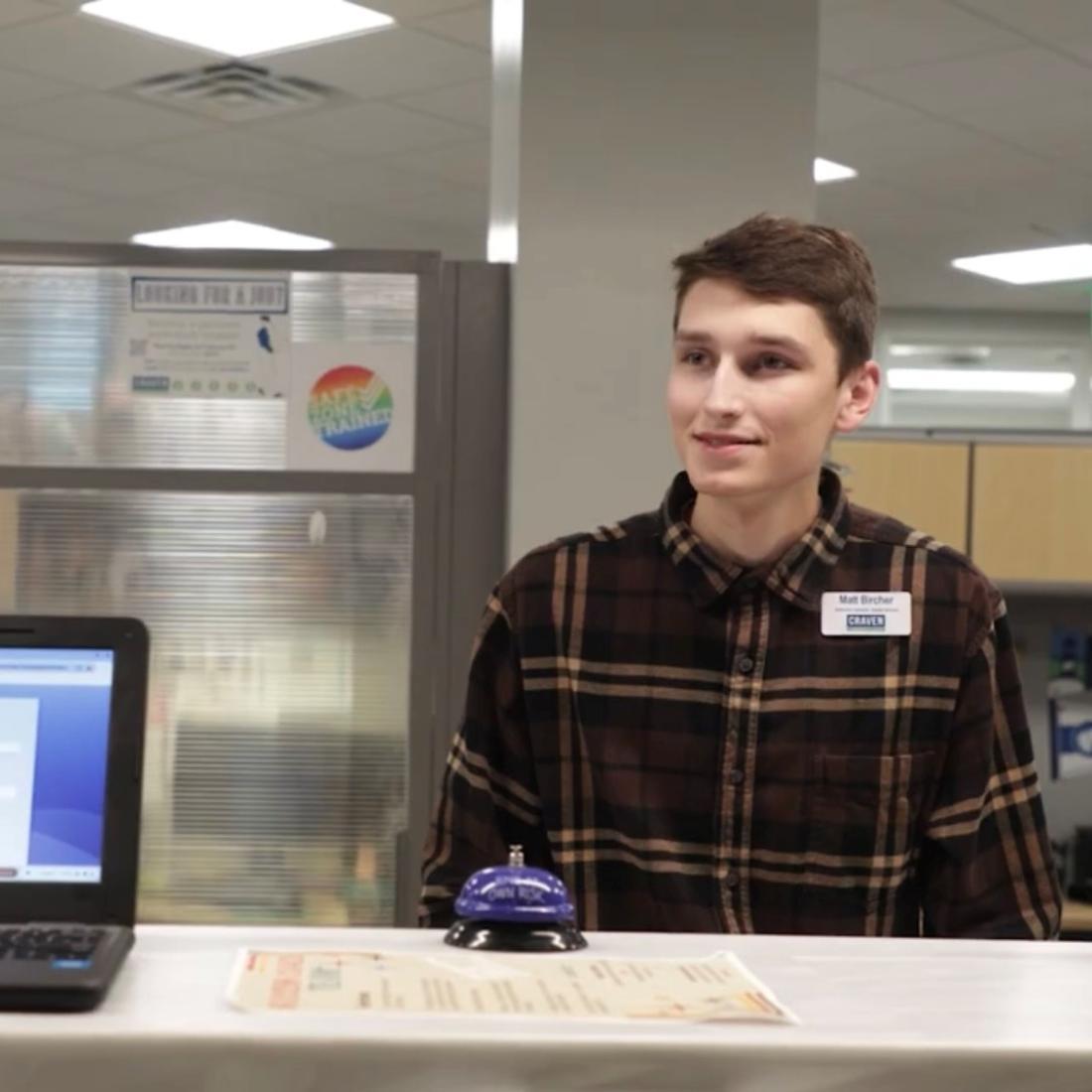 Alum and Craven employee Matt Bircher helps a student at the admissions front desk