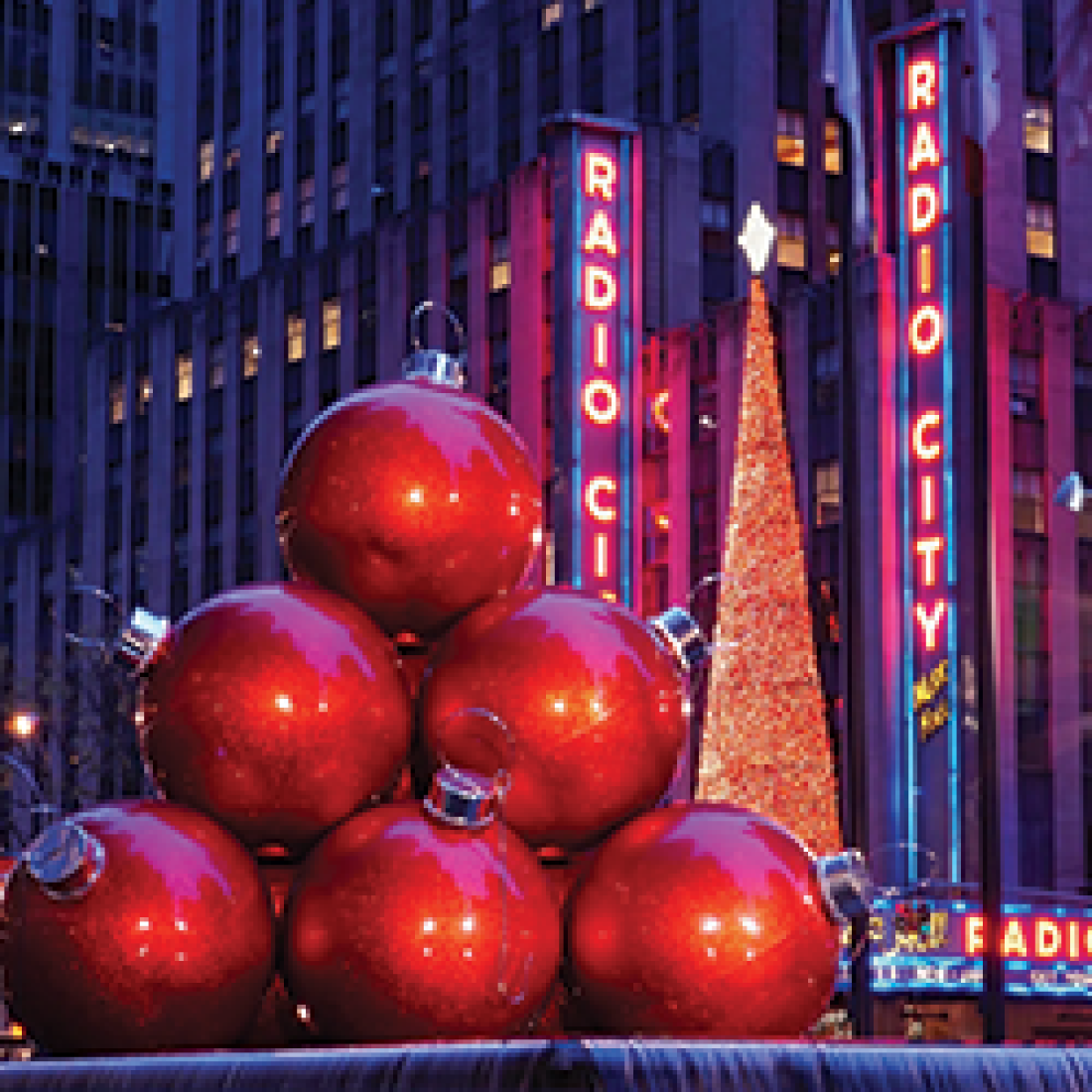 Six giant red ornaments stacked to form a triangle in front of Radio City Music Hall