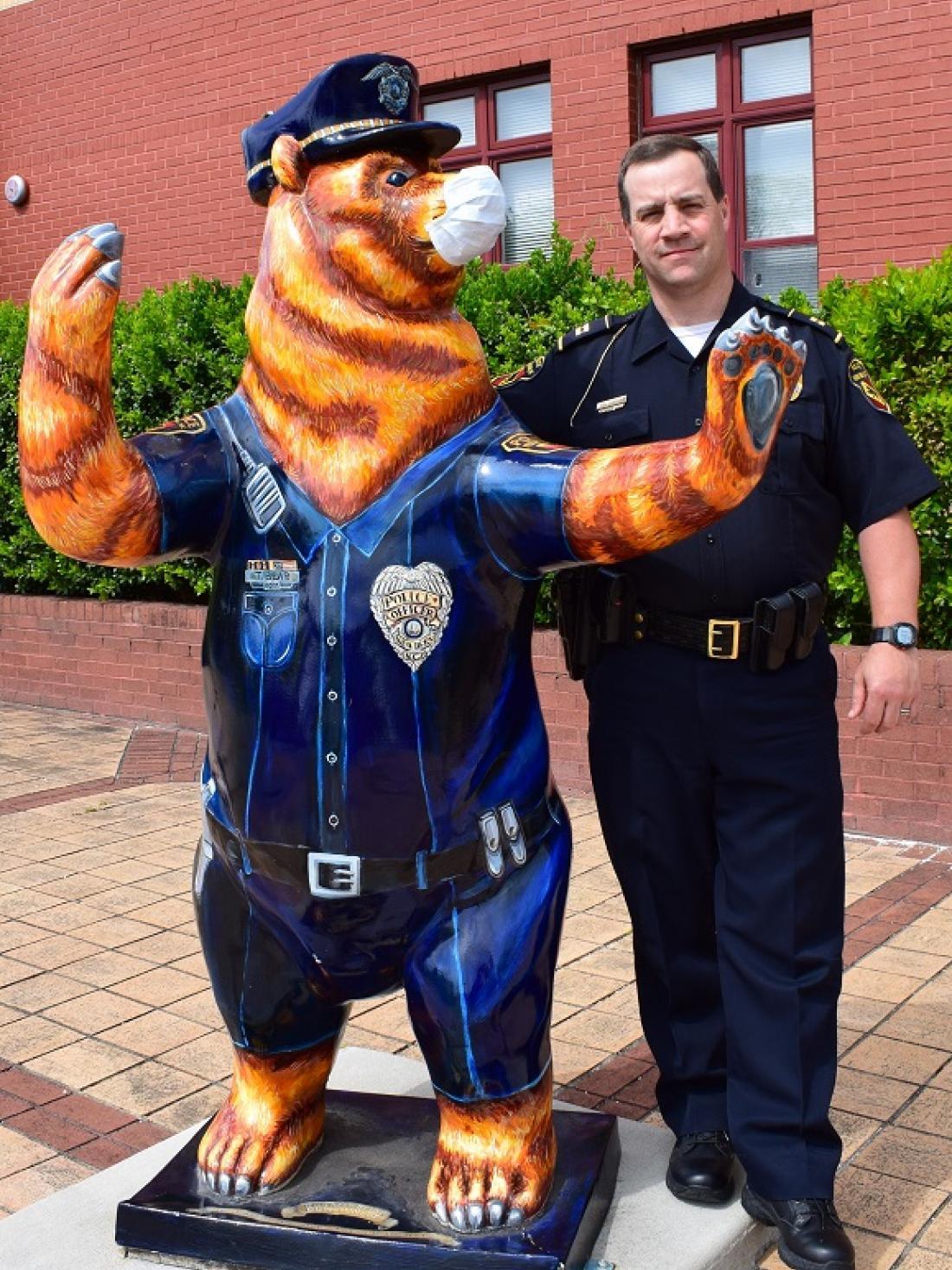 Criminal Justice instructor and policeman David Daniels poses next to bear statue at police station