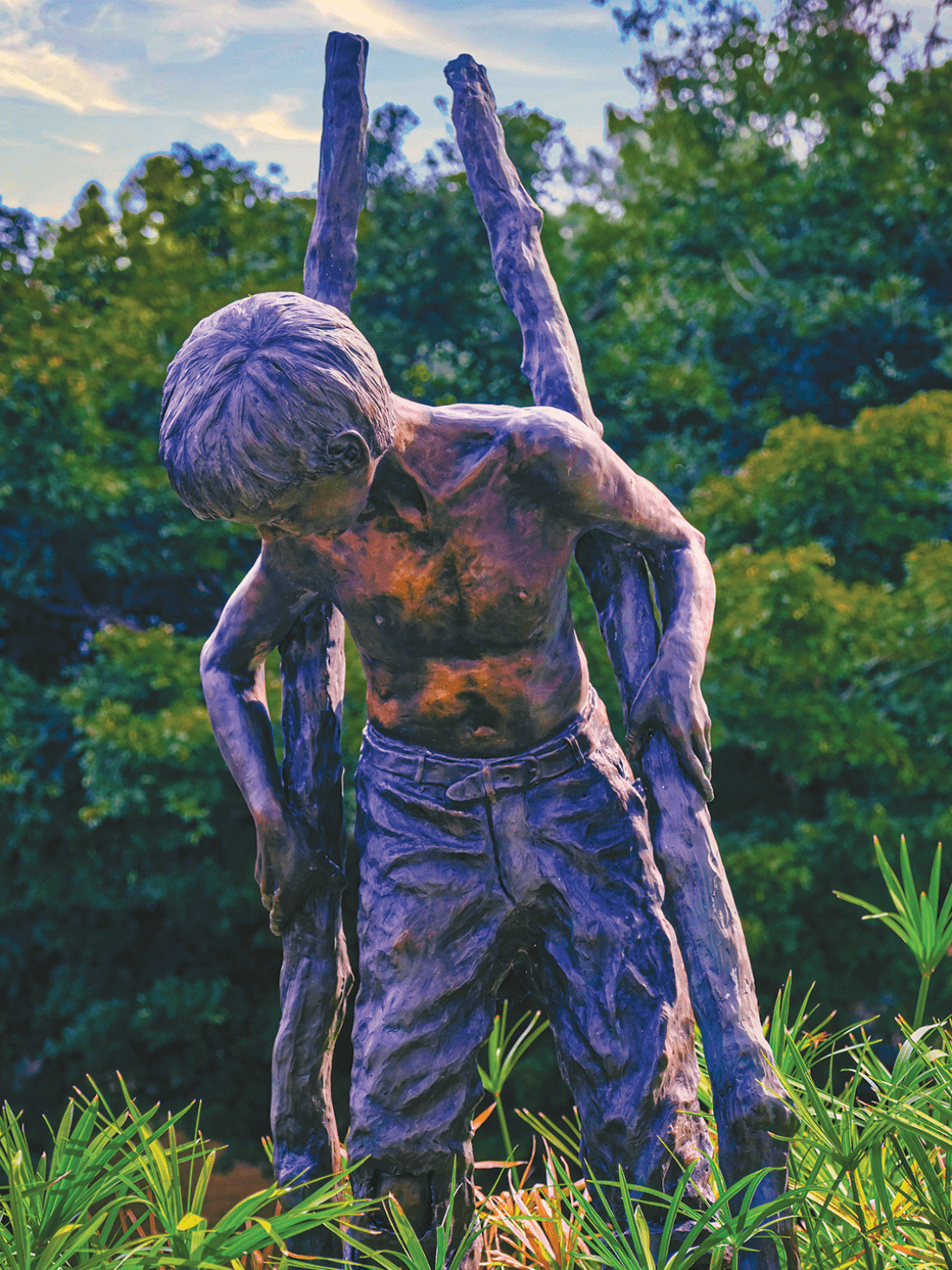 Bronze statue of young shirtless boy on stilts