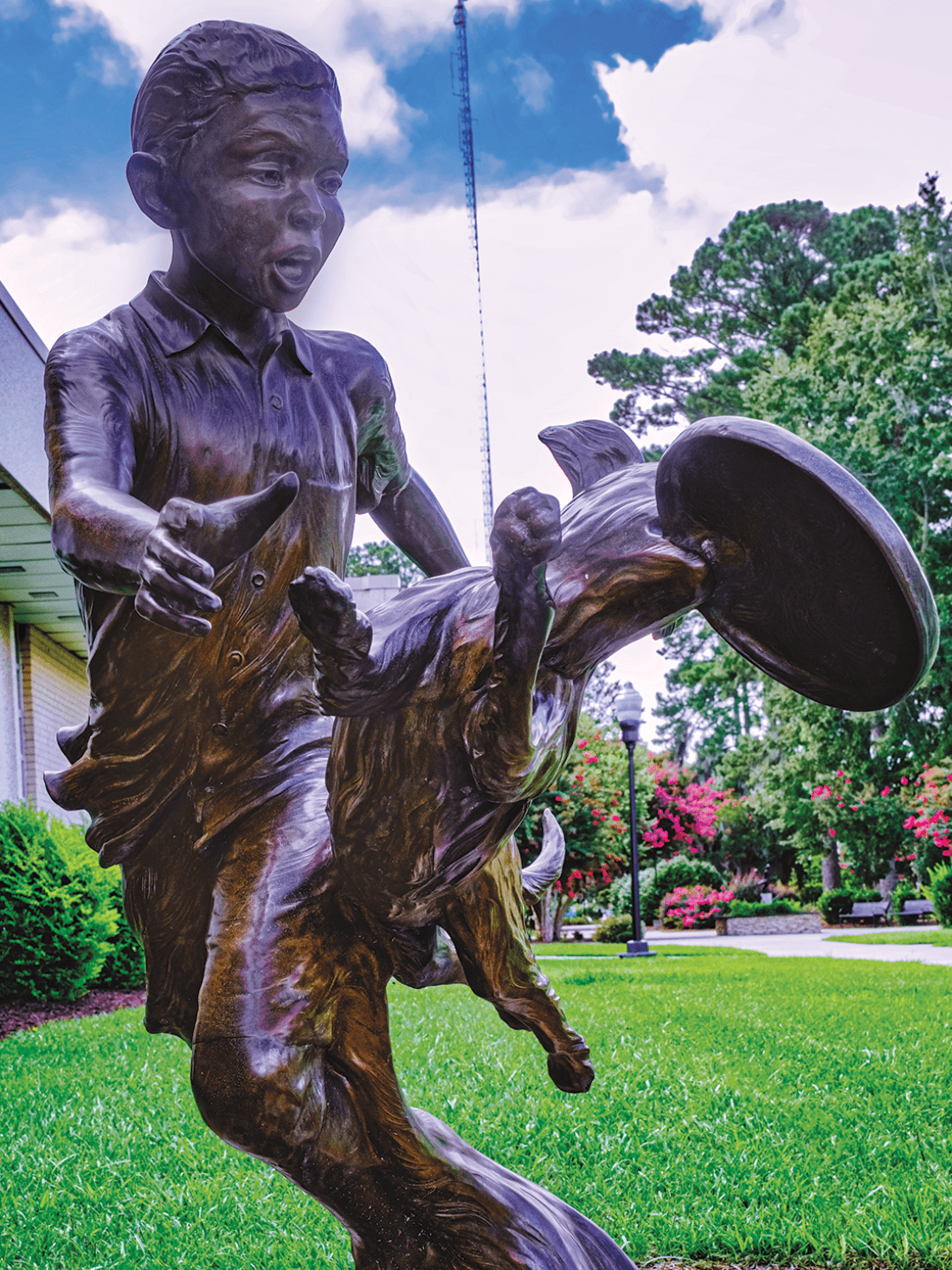 Bronze statue of boy and dog with frisbee