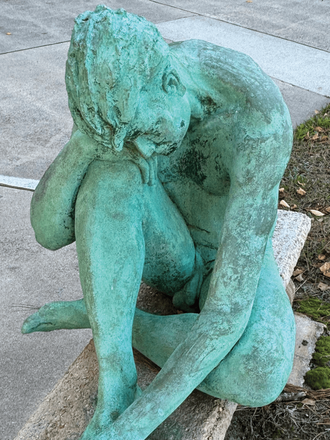 Bronze statue of life-sized nude male on a bench