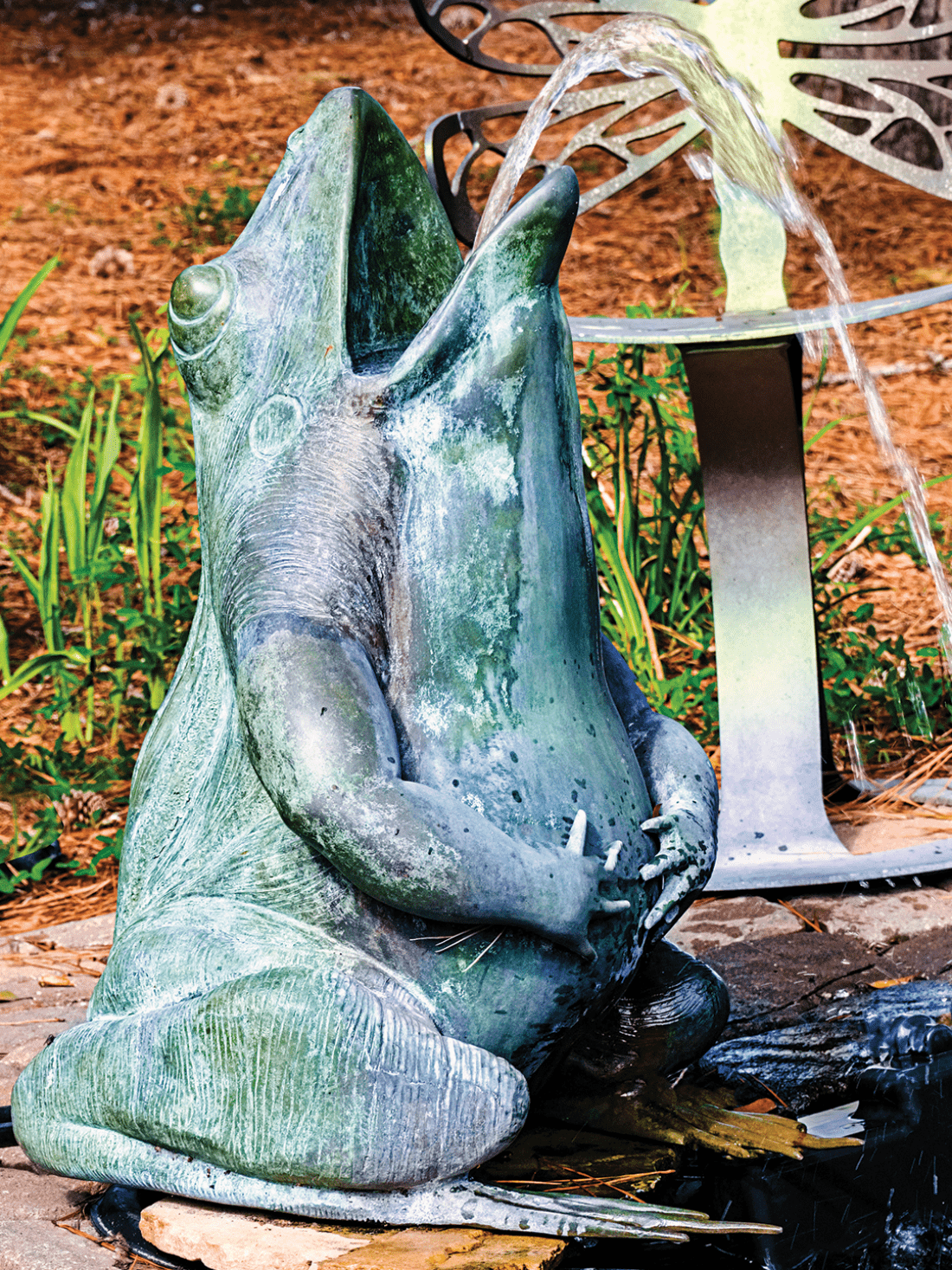Bronze frog fountain statue spewing water out of its mouth