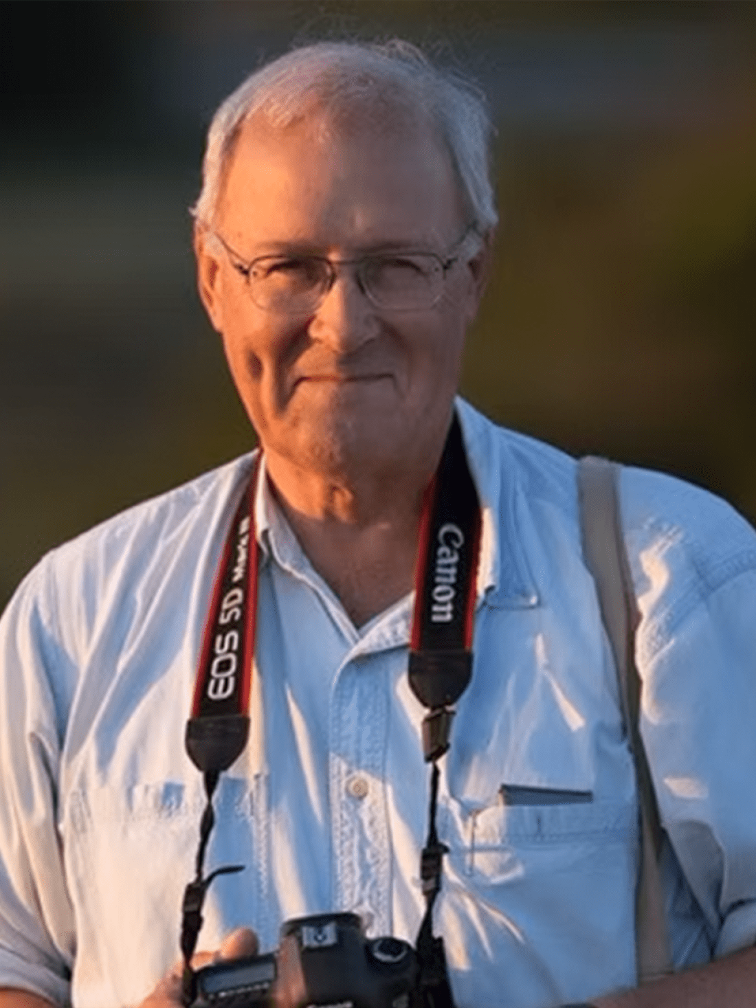 Dr. John McQuade poses while wearing a Canon camera with strap