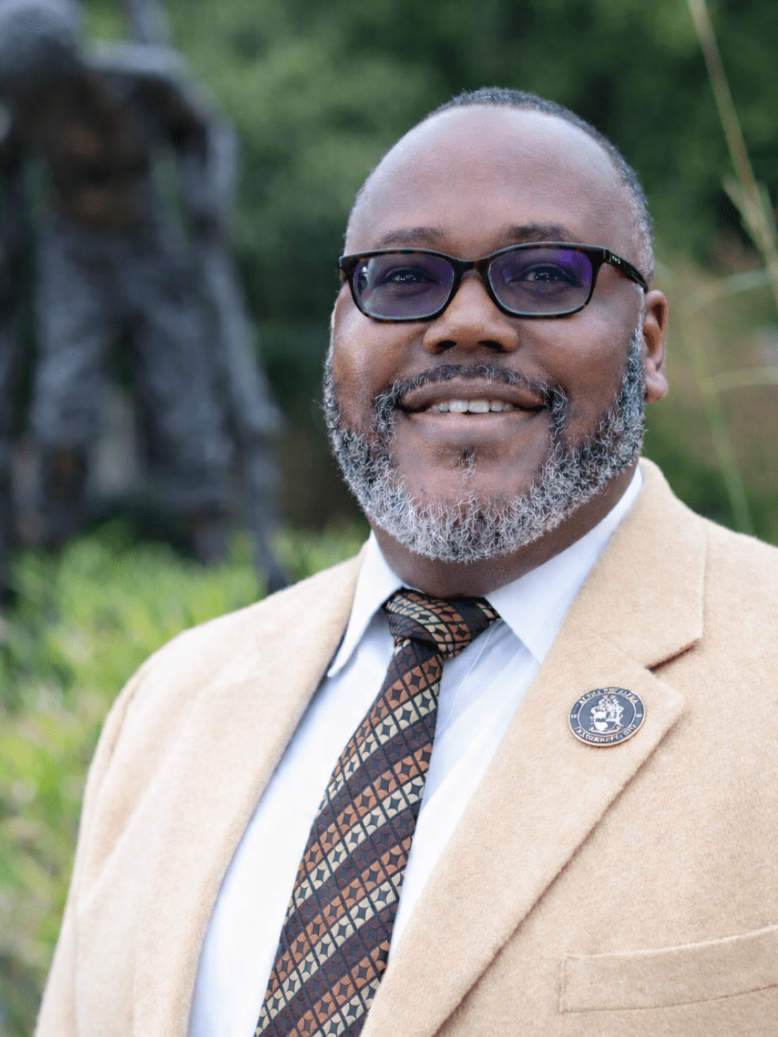 Man in suit jacket stands in front of statue