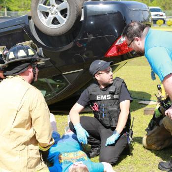 EMT students help an injured person next to a flipped car
