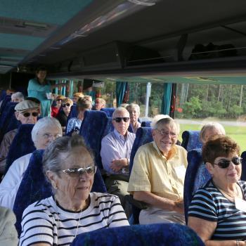 Group of older adults sit in a tour bus