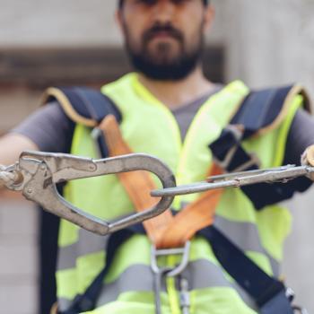 Construction worker makes sure harness is securely hooked