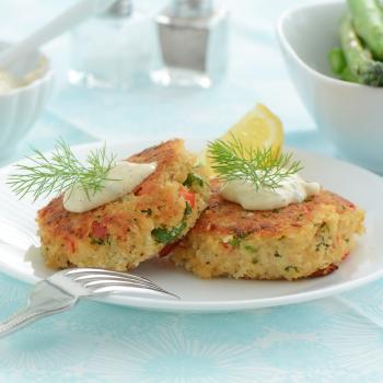 Plate of two crab cakes topped with cream and garnish with fork