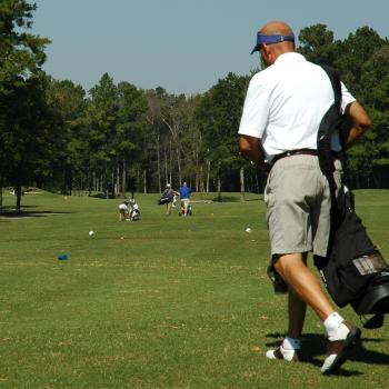 Men walking on golf course with bags of clubs