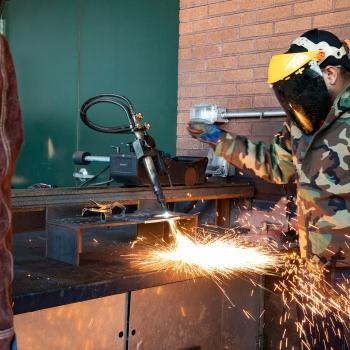 Two welding students practice welding outside