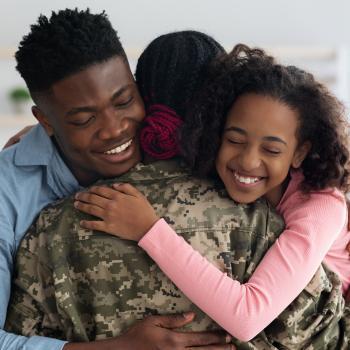Adult male and teenaged female hug female soldier