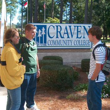 Three students standing outside by the Craven CC entrance sign in 2000s