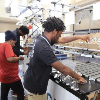 Two males and one female student work on a mock assembly line