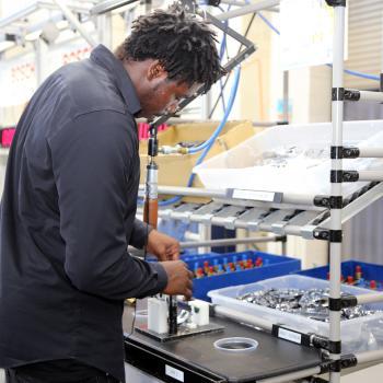 Male student works on mock assembly line
