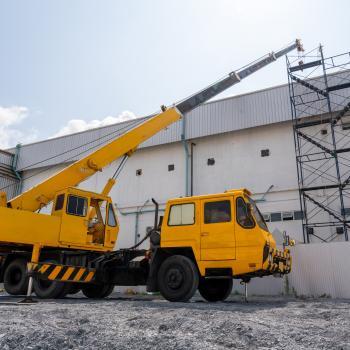A yellow and black mobile crane at roof repair in construction site