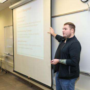 Instructor presenting a lesson on types of management in a classroom.