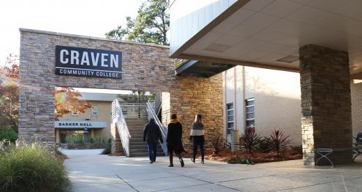 Students walking outside under exterior sign
