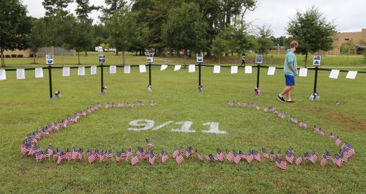 Tiny American flags staked in the ground around white spray-painted "9/11" for September 11th remembrance event