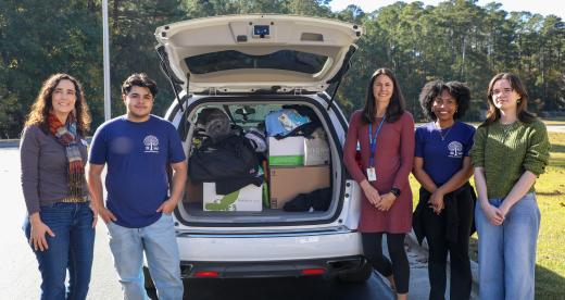 Students and advisors of Craven's Phi Theta Kappa chapter load donations into a car trunk.