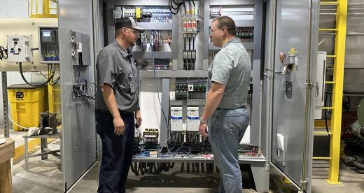 Chatsworth employees Cody Marshall and Stephen Calabro stand in front of an industrial control panel