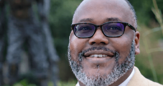 Man in suit jacket stands in front of statue