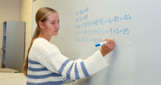 Student Sarah Fedyna writes math problem on whiteboard