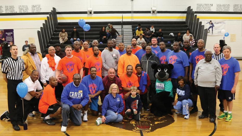 College employees on basketball court with Knight the Panther mascot in 2010s